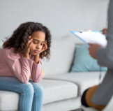 unhappy girl listening to psychologist at meeting